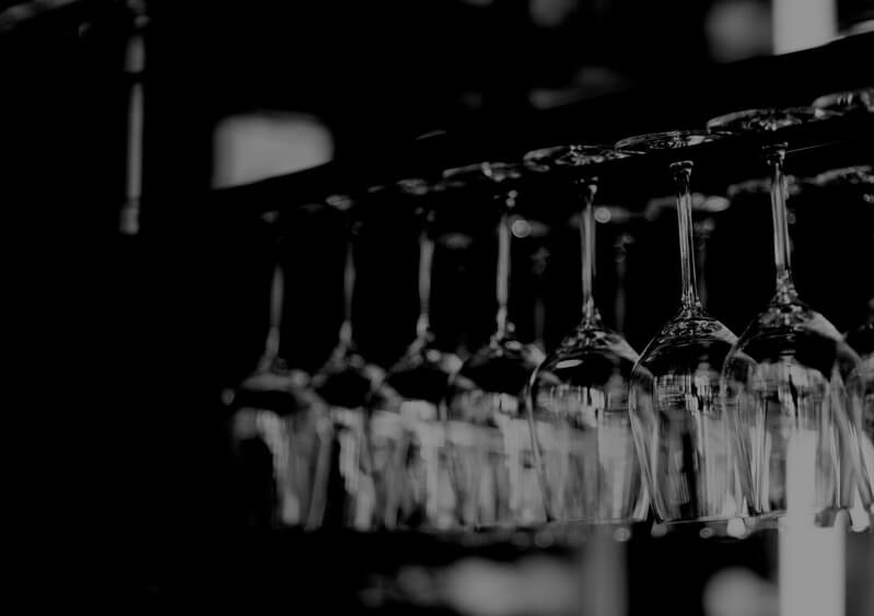 Grayscale image of wine glasses hanging from a rack